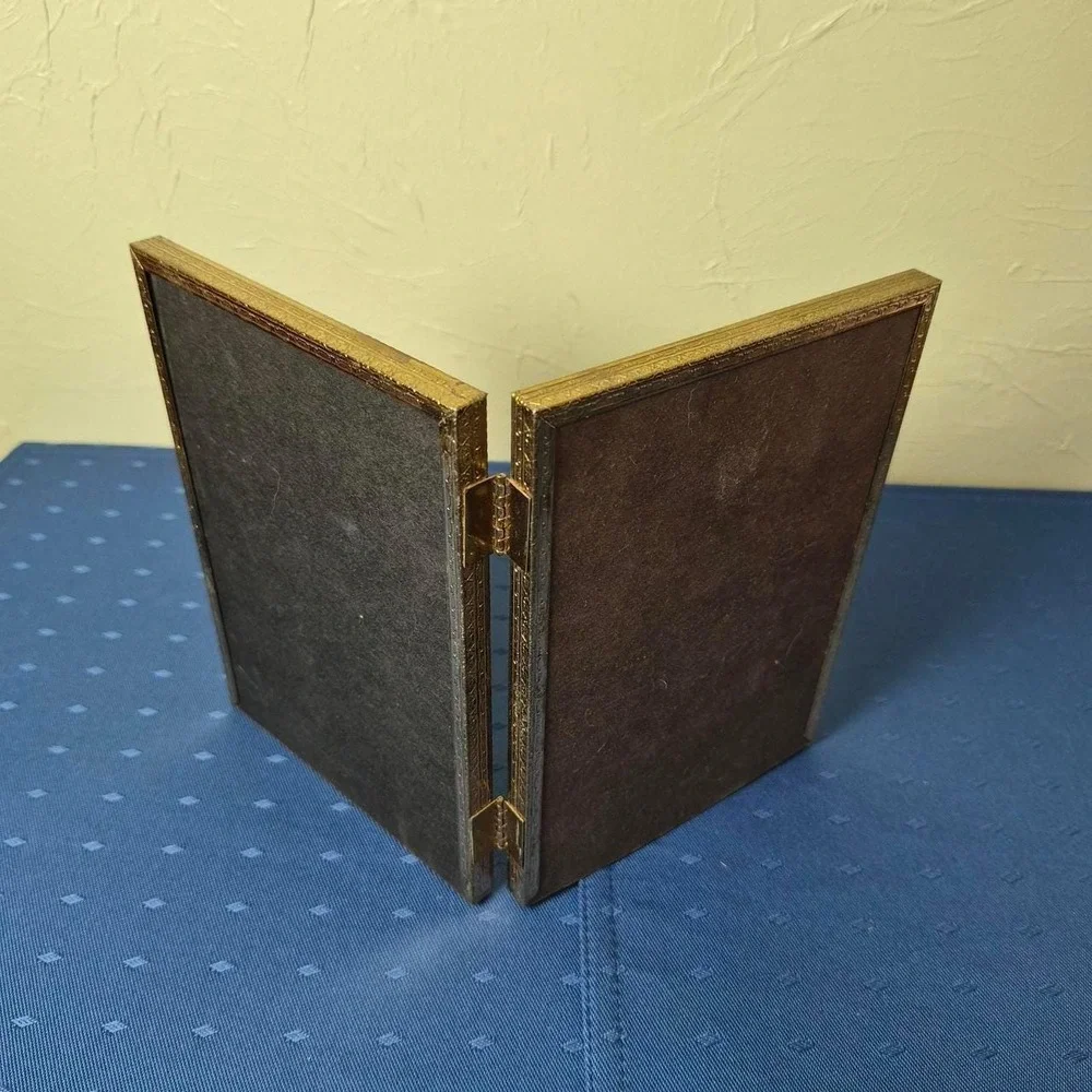 Vintage hinged gold picture frame with vertical ridges.